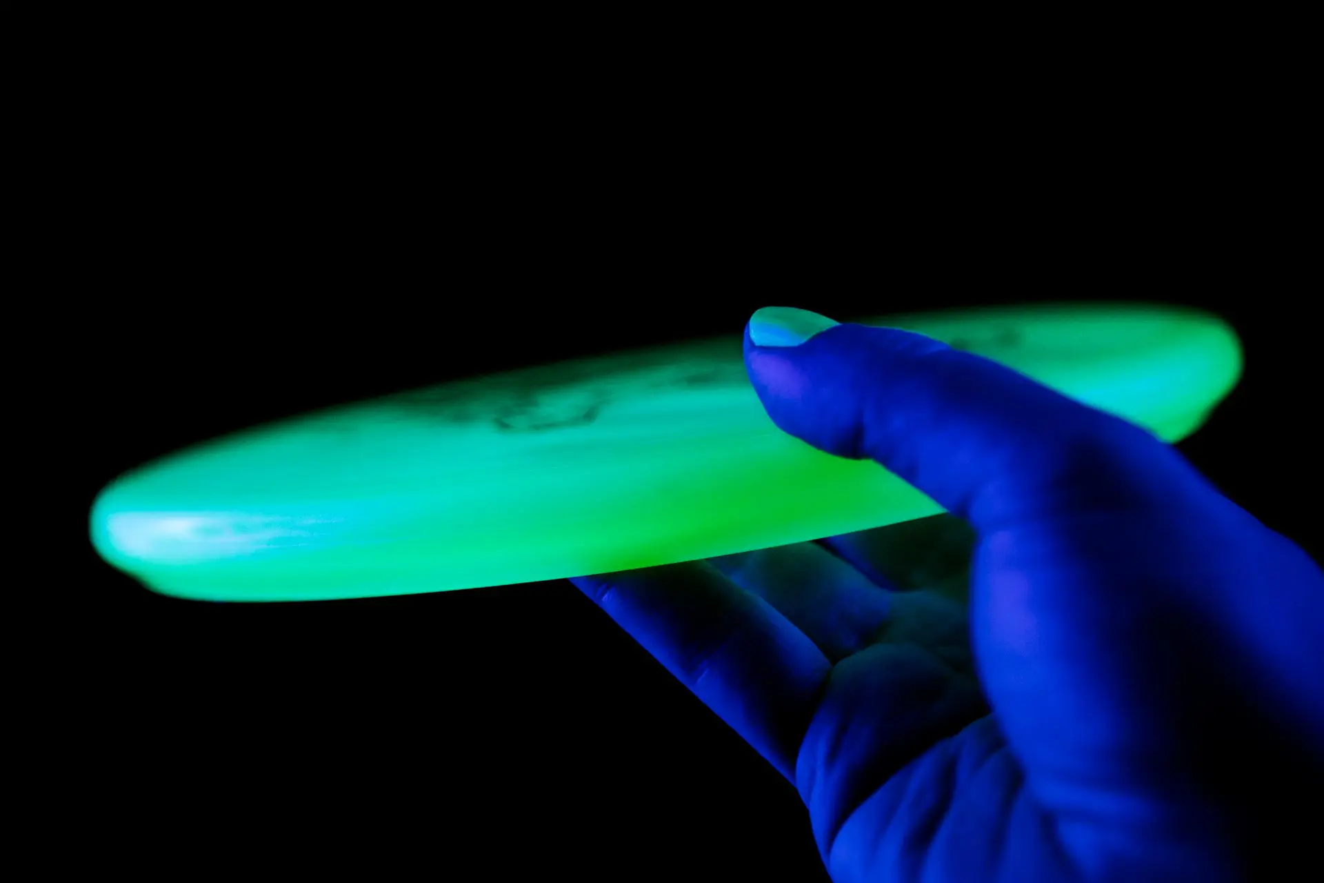 Hand Holding a UV Glowing Disc Golf Flying Disc